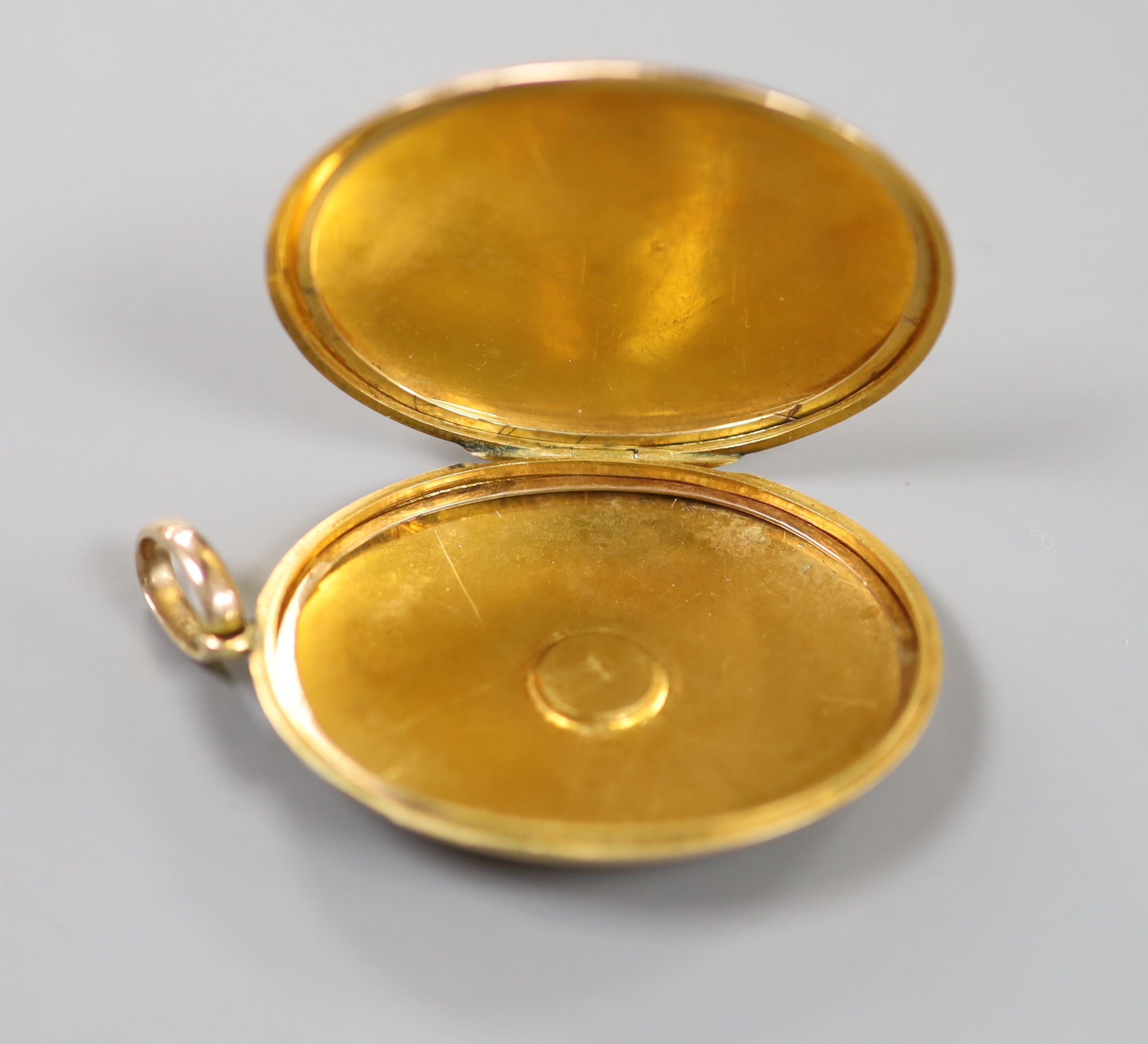 An early 20th century engraved yellow metal (stamped 9c) and split pearl set oval locket, 44mm, gross weight 13.5 grams, with engraved monogram.